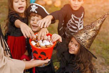 Joyful kids in Halloween costumes eating candies