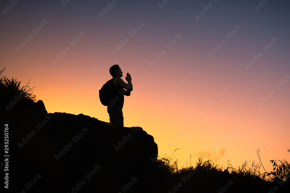 Silhouette of man praying at sunset. 