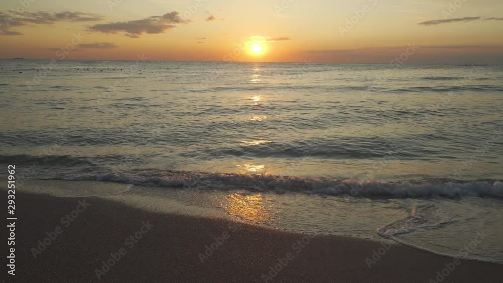 Sunset view from beach, waves crashing on sand beach Sunset view from beach, waves crashing on sand beach
