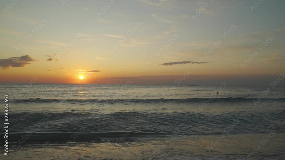 Sunset view from beach, waves crashing on sand beach