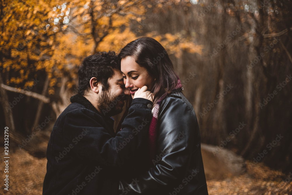 Couple in love caressing on autumn in the autumnal forest, enjoying a beautiful day. Couple kissing in the colorful orange and yellow park. Couple in love caressing on autumn in the autumnal forest, enjoying a beautiful day. Couple kissing in the colorful orange and yellow park.