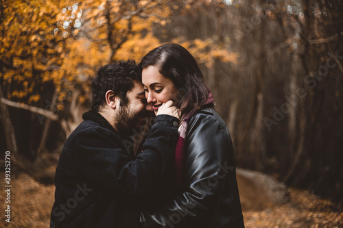 Couple in love caressing on autumn in the autumnal forest, enjoying a beautiful day. Couple kissing in the colorful orange and yellow park.