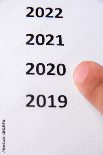 Finger that points to 2020. White paper. Copy sapce