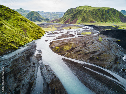 An aerial shot of a river flowing through a moss covered valley in southern Iceland.