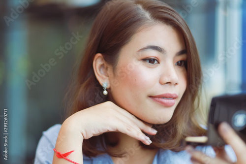 Asian woman make up her face with lipstick in cafe