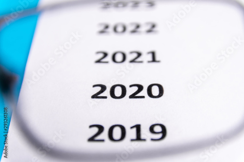 List of recent years on white paper. Focus on 2020. View through glasses Copy Space