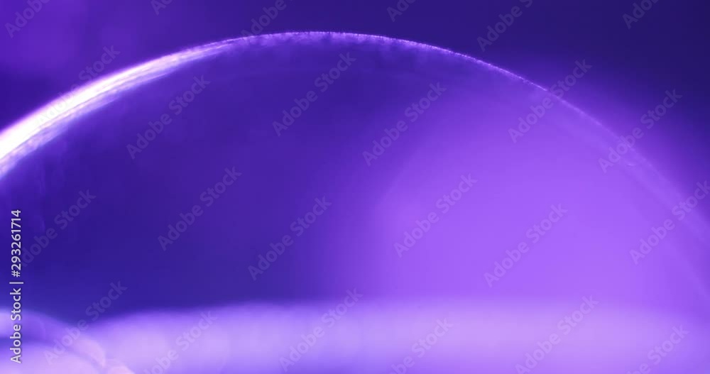 Macro shot of the current on a purple sphere. Stream of small dust particles flowing around on the surface. Light moves to the right, sphere in the dark. Macro shot of the current on a purple sphere. Stream of small dust particles flowing around on the surface. Light moves to the right, sphere in the dark.