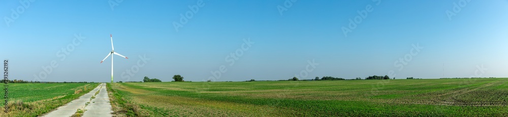 wind generators on a green field under a blue sky on a bright sunny day, panorama