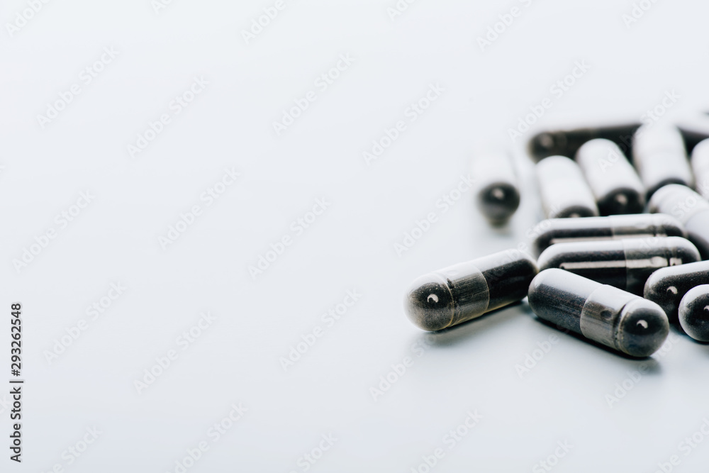 selective focus of black pills on white background with copy space selective focus of black pills on white background with copy space