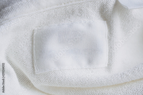 Blank white clothes label on new cotton shirt background
