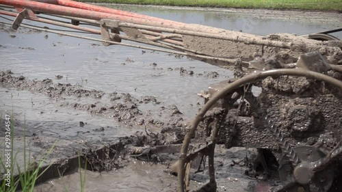 Farmer working with a handheld motor plow in a rice field.life of countryside.