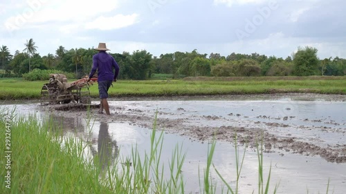 Farmer working with a handheld motor plow in a rice field.life of countryside.