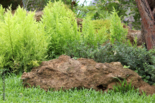 Large stone in a garden placed on a green grass.