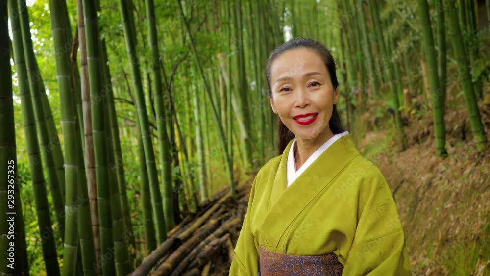 Elegant Japanese woman walking through a bamboo forest in Kyoto Japan Elegant Japanese woman walking through a bamboo forest in Kyoto Japan