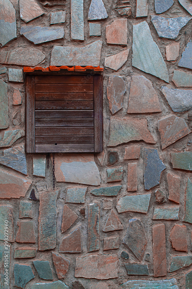 Stone wall exterior with small window closed with old wooden door, background with good texture. Vertical. For text and creative design Stone wall exterior with small window closed with old wooden door, background with good texture. Vertical. For text and creative design