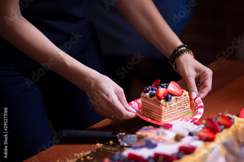 women's hands cut off a piece of cake at a party