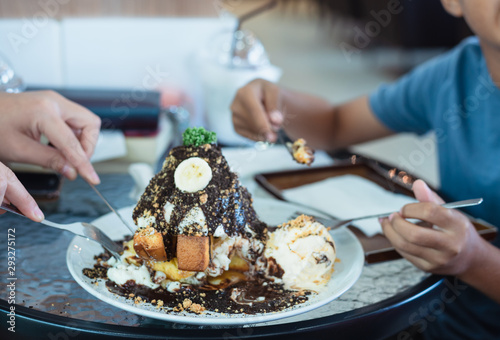 Selective focus ice cream cake with enjoying family eat honey banoffee toast menu in white dish on table at restaurant.Eating party concept.