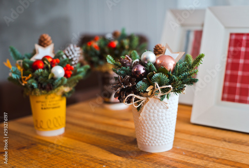 Gift mini bouquets of fir branches in cones toy cups on wooden table background.