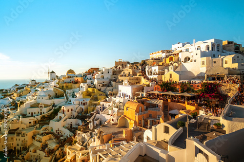 Beautiful view of Oia with traditional white houses and windmills in village, Santorini island, Greece