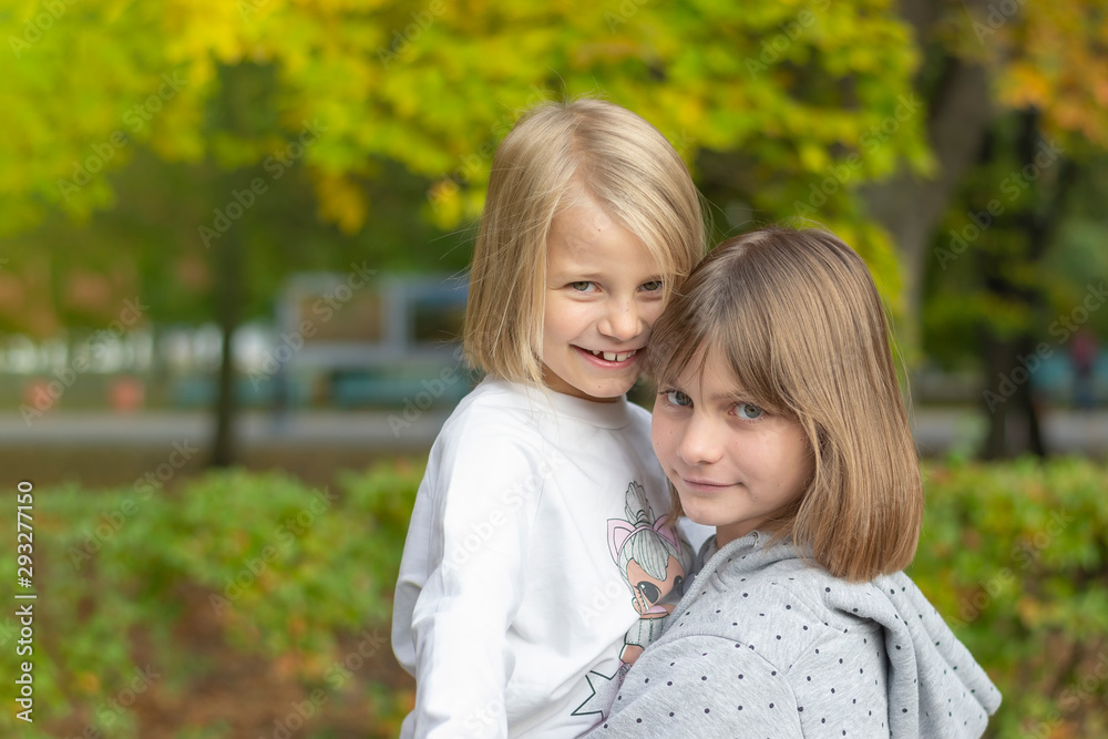 Two happy girls are playing in the autumn park. Smiling and hugging Two happy girls are playing in the autumn park. Smiling and hugging