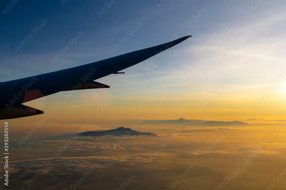 Sunset sky and view on mountains in clouds from the airplane window Sunset sky and view on mountains in clouds from the airplane window