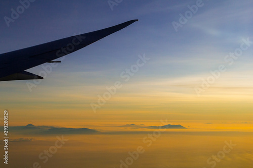 Sunset sky and view on mountains in clouds from the airplane window