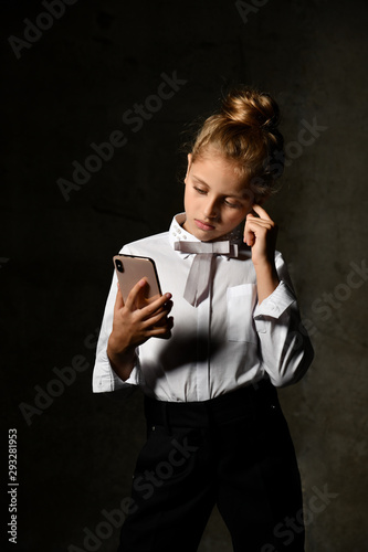 Little female caucasian model posing in school uniform on a gray concrete studio background. photo