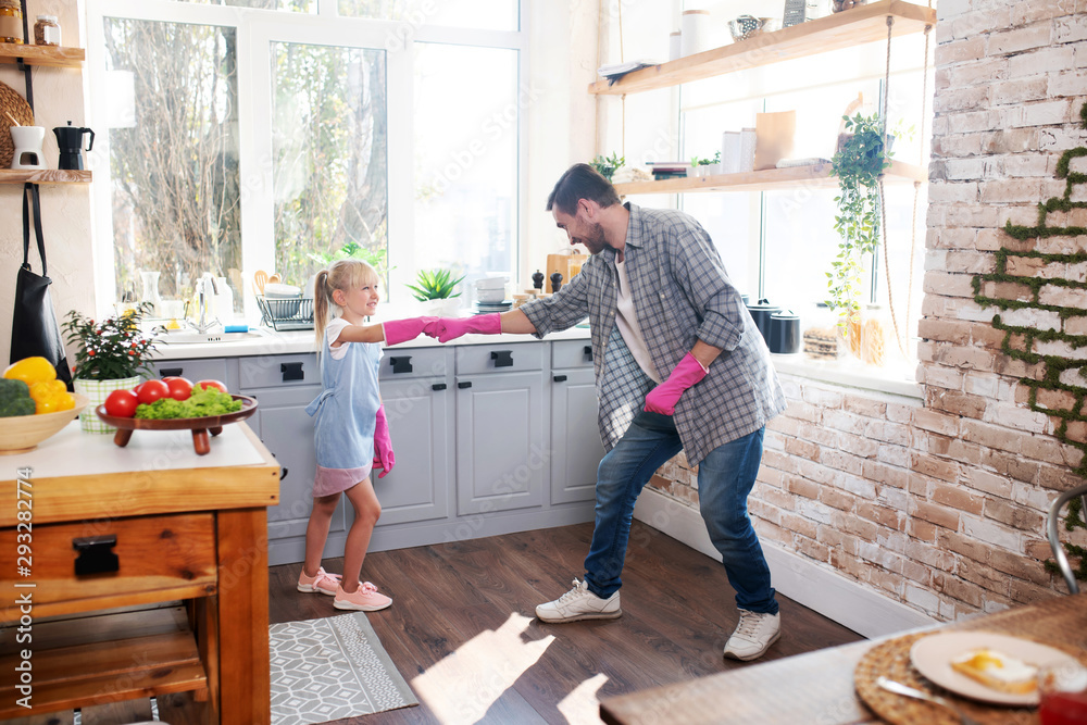 Girl feeling excited before cleaning kitchen with daddy - obrazy, fototapety, plakaty 