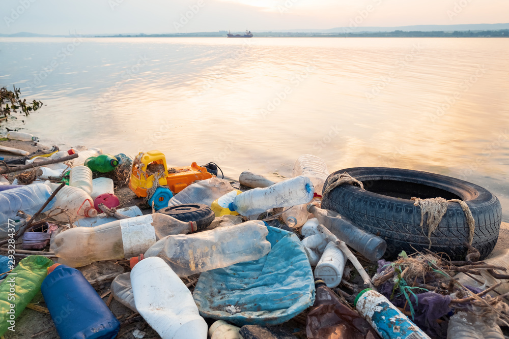 Calm surface of sea water with floating plastic bottles and garbage, polluted seashore with plastic garbage at sunset view from drone. Environmental pollution. Ecological problem Calm surface of sea water with floating plastic bottles and garbage, polluted seashore with plastic garbage at sunset view from drone. Environmental pollution. Ecological problem