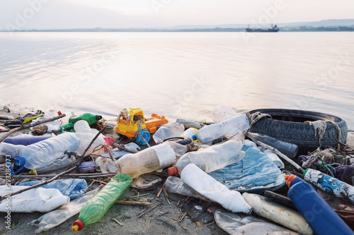Spilled garbage on the beach of a big city on a sunset day. Empty used dirty plastic bottles, household rubbish. Dirty sea, sandy coast of the Black Sea. Environmental pollution. Ecological problem