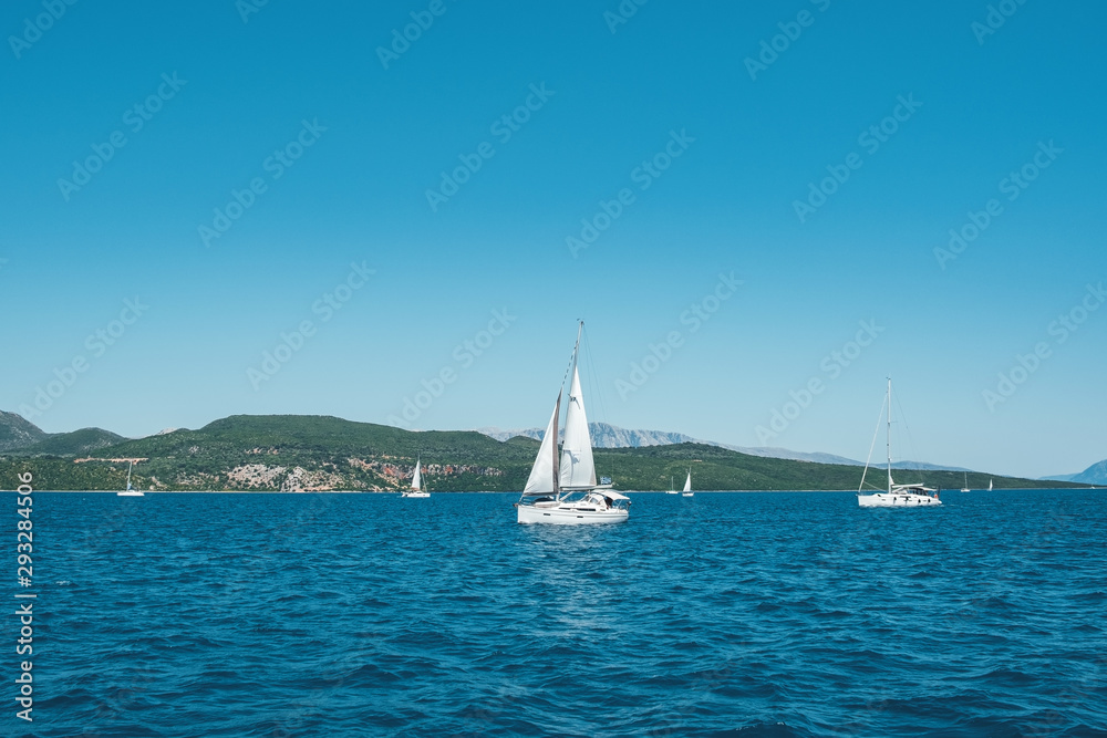 Sailing yacht anchored in a marina in the harbor near the seaside resort town of Privieza, Greece. Slight excitement of the sea surface and a view of the mountain tops of the island. Tourism