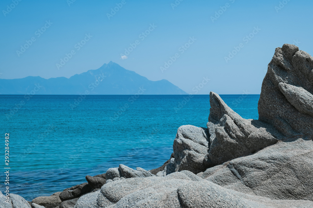 Mount Athos in Greece on a sunny day in summer against a blue sky. Beautiful silhouette of Mount Athos in Greece in the Aegean Sea. Calm seawater surface.
