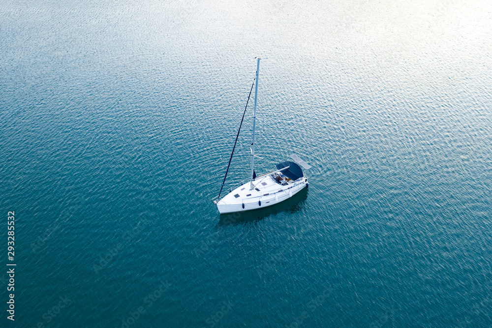 Aerial view of a slide from a drone on a pleasure sailing vessel sailing along the waves over the sea. The texture of the masts and ropes, mountain peaks, blue sea and blue sky in summer Aerial view of a slide from a drone on a pleasure sailing vessel sailing along the waves over the sea. The texture of the masts and ropes, mountain peaks, blue sea and blue sky in summer