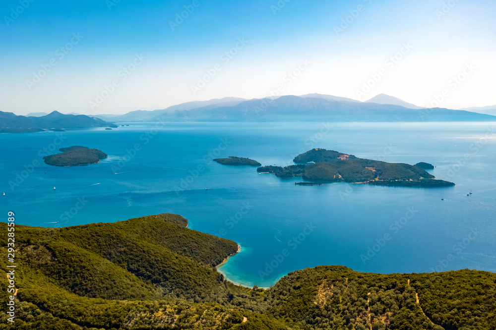 Aerial view from a drone on a panorama of the blue sea, picturesque islands and mountains in Greece, in summer on a sunny day. Beautiful coastline of the resort town. Tourism