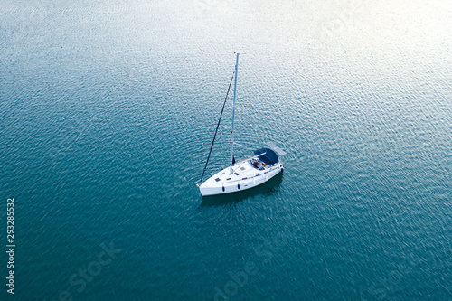 Aerial view of a slide from a drone on a pleasure sailing vessel sailing along the waves over the sea. The texture of the masts and ropes, mountain peaks, blue sea and blue sky in summer