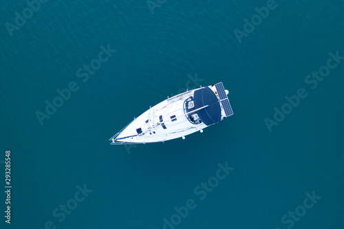Aerial view of a slide from a drone on a pleasure sailing vessel sailing along the waves over the sea. The texture of the masts and ropes, mountain peaks, blue sea and blue sky in summer © marina_larina