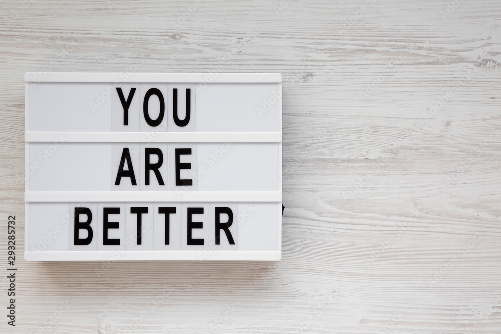 'You are better' words on a lightbox on a white wooden background, top view. Overhead, from above. Flat lay. Copy space. 'You are better' words on a lightbox on a white wooden background, top view. Overhead, from above. Flat lay. Copy space.