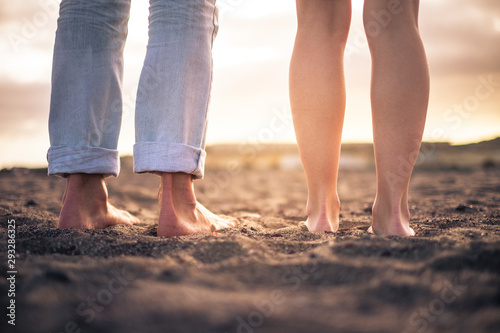 Close up of nudes couple feet for romantic and romance love concept - free people barefoot on the beach looking the sunset and enjoying love couple together