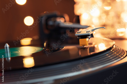 Turntable vinyl record player. Sound technology for DJ to mix and play music. Stylus with a needle on a vinyl record. Label. Bright party lights illuminate the surface of the plate. Christmas lights