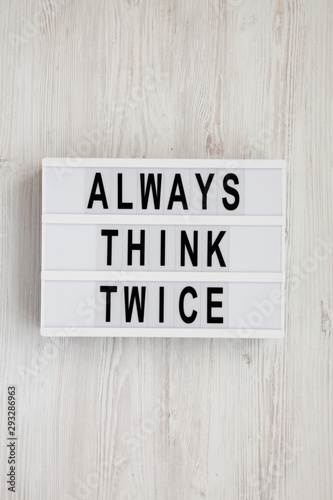 'Always think twice' words on a lightbox on a white wooden background, top view. Overhead, from above, flat lay. 