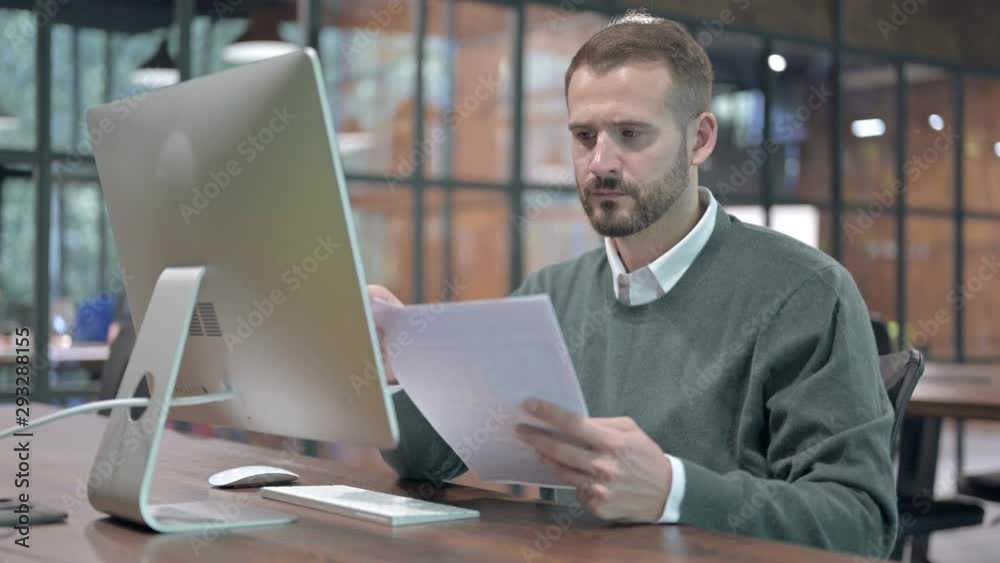 Ambitious Man Reading Document on Office Desk Ambitious Man Reading Document on Office Desk