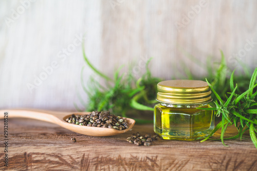 Hemp seeds and hemp oil in a glass jar on a green marijuana leaf background. medical marijuana concept  CBD cannabis OIL.