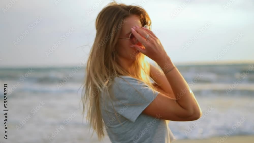 Young female felling fun and free and straightens her hair on beach at sunset. Carefree girl on tropical beach runs into refreshing sea at golden sunrise. Happy tourist woman on summer vacation. Young female felling fun and free and straightens her hair on beach at sunset. Carefree girl on tropical beach runs into refreshing sea at golden sunrise. Happy tourist woman on summer vacation.