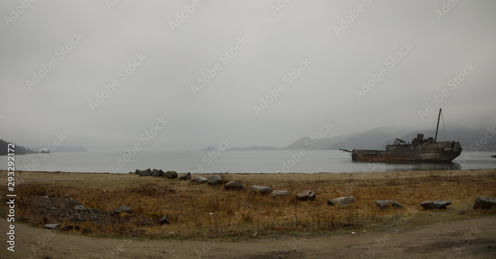 An old wooden shipwreck whaling boat abandoned stand on beach on foggy morning sad panoramic view