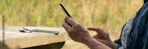 Close up view of modern senior lady hands with a smartphone