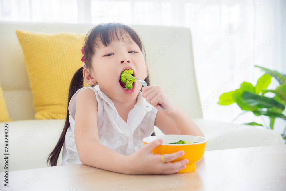 Little asian girl eating broccoli at home,Healthy food for child concept. Little asian girl eating broccoli at home,Healthy food for child concept.