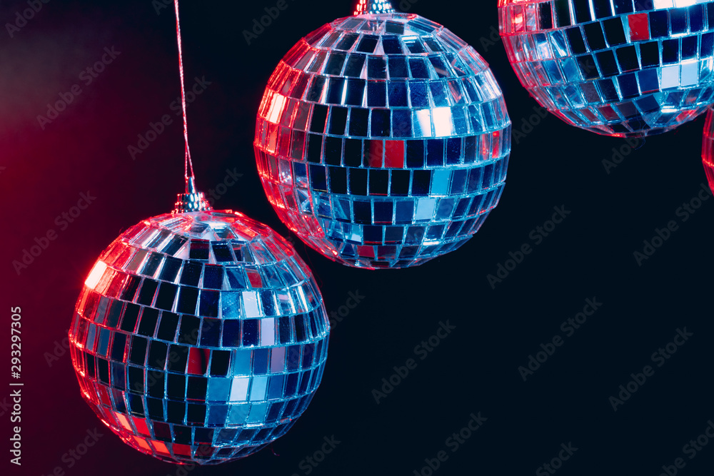 Fototapeta premium Sparkling disco balls hanging in the air against black background