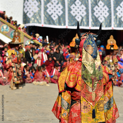 Tawang, Arunachal Pradesh, India, Buddhist monk dancing in disguise for the Torgya festival, in the background there are monastery and many gathered viewers.