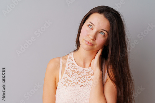 Image of thinking young woman standing over a gray background.