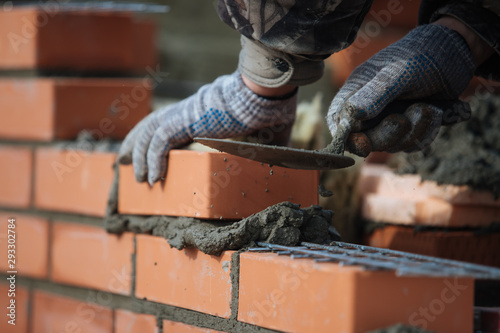 Fotobehang Brick wall contruction with mason hands